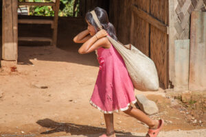 Ban Kiu Kam Pone è un villaggio di etnia Khmu. Questa bambina trasporta un sacco di riso tenendolo sulla schiena e sostenendolo con una cinghia che passa sulla fronte.