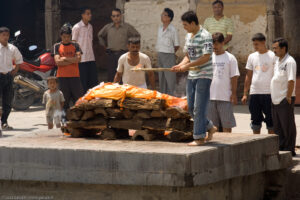 Un corpo avvolto nel sudario viene cremato in uno dei sei ghat per la cremazione del tempio di Pashupatinath